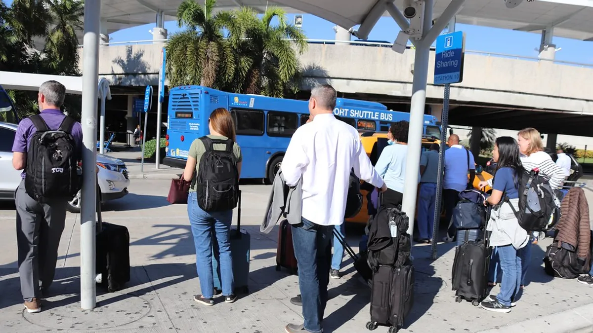 Travellers with luggage waiting inside a busy airport terminal